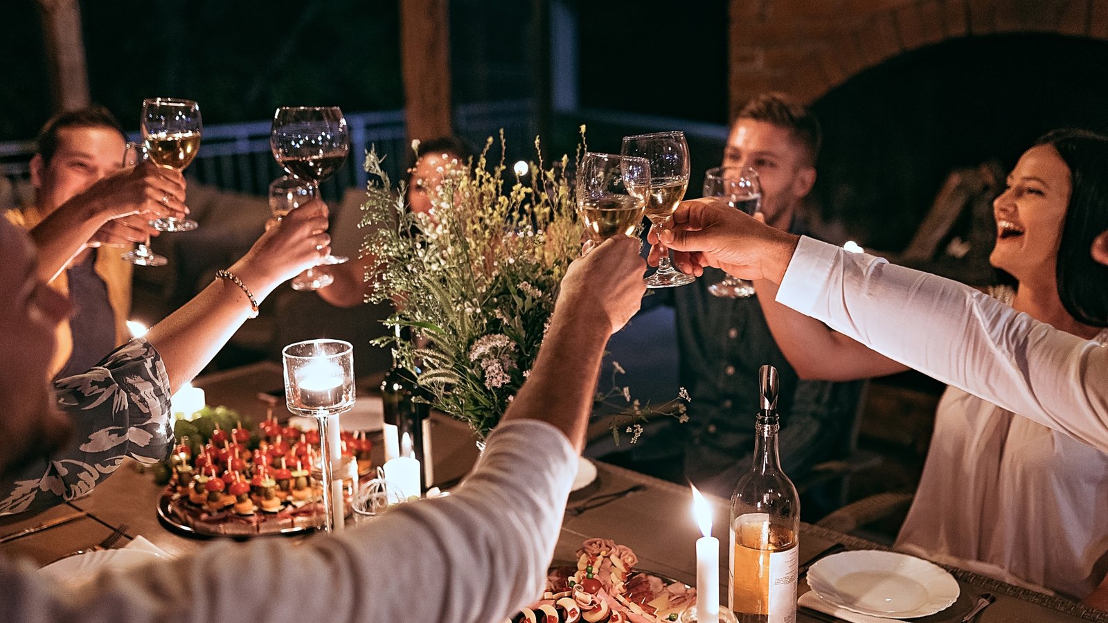 How Singles Socials works: friends raising a toast together over dinner